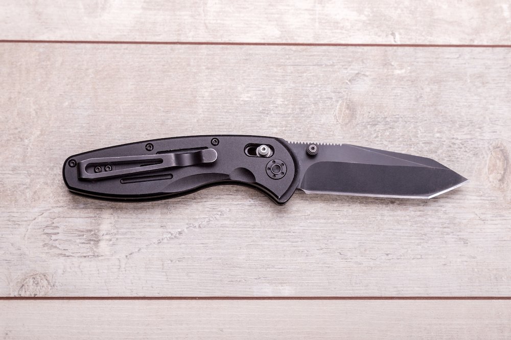 Folding knife on a wooden background - The Skilled Survivor
