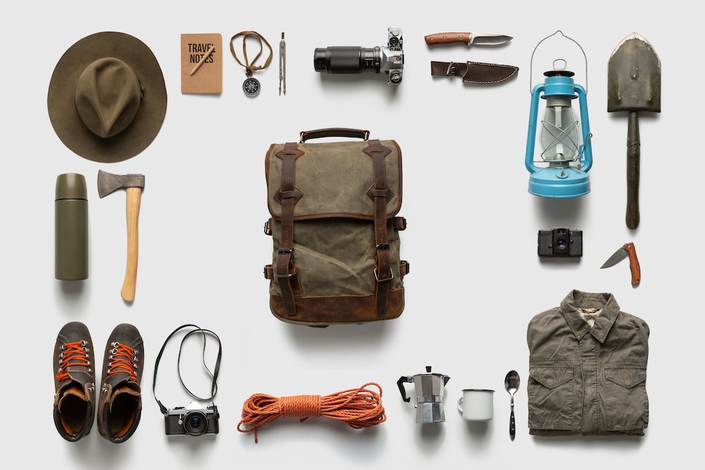 Packing backpack for a trip concept with traveler items isolated on white background - The Skilled Survivor