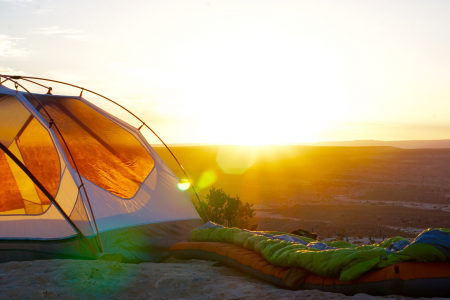 tent set up at sunset with sleeping bags rolled out on mountain